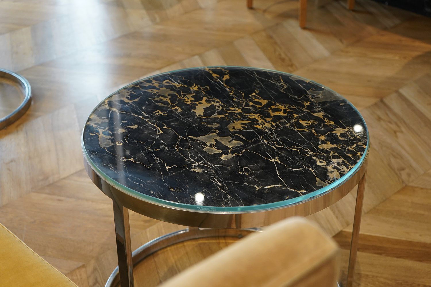 A round Portoro Gold marble side table on a herringbone floor, Blakemore Hyde Park - Roma Marble