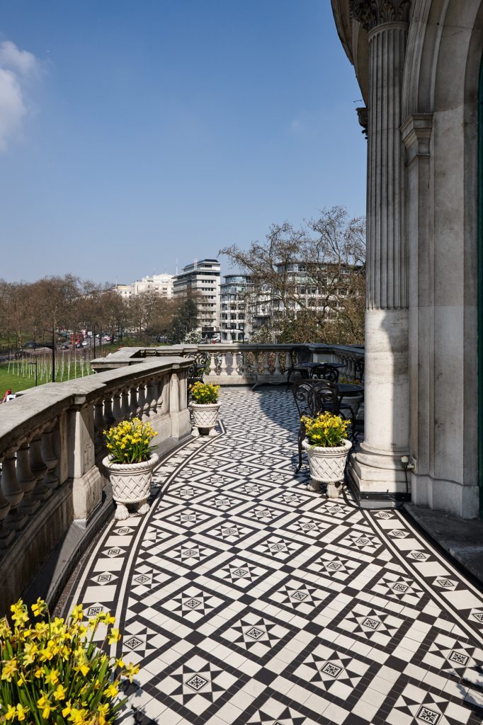 An upper terrace laid in Victorian-pattern stone tiles — Les Ambassadeurs, Roma Marble