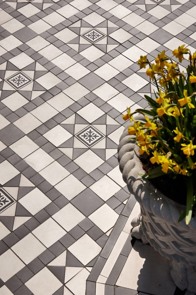 An upper terrace laid in Victorian-pattern stone tiles — Les Ambassadeurs, Roma Marble