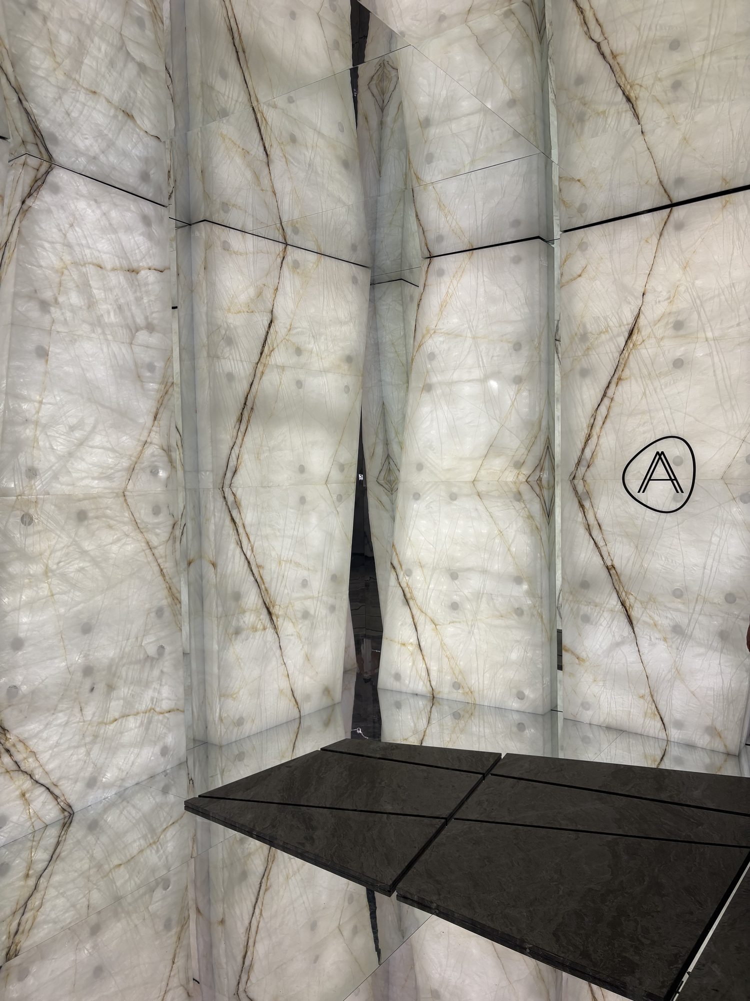 Bookmatched quartzite walls meeting in a mirrored corner at the Antolini installation, Marmomac 2026