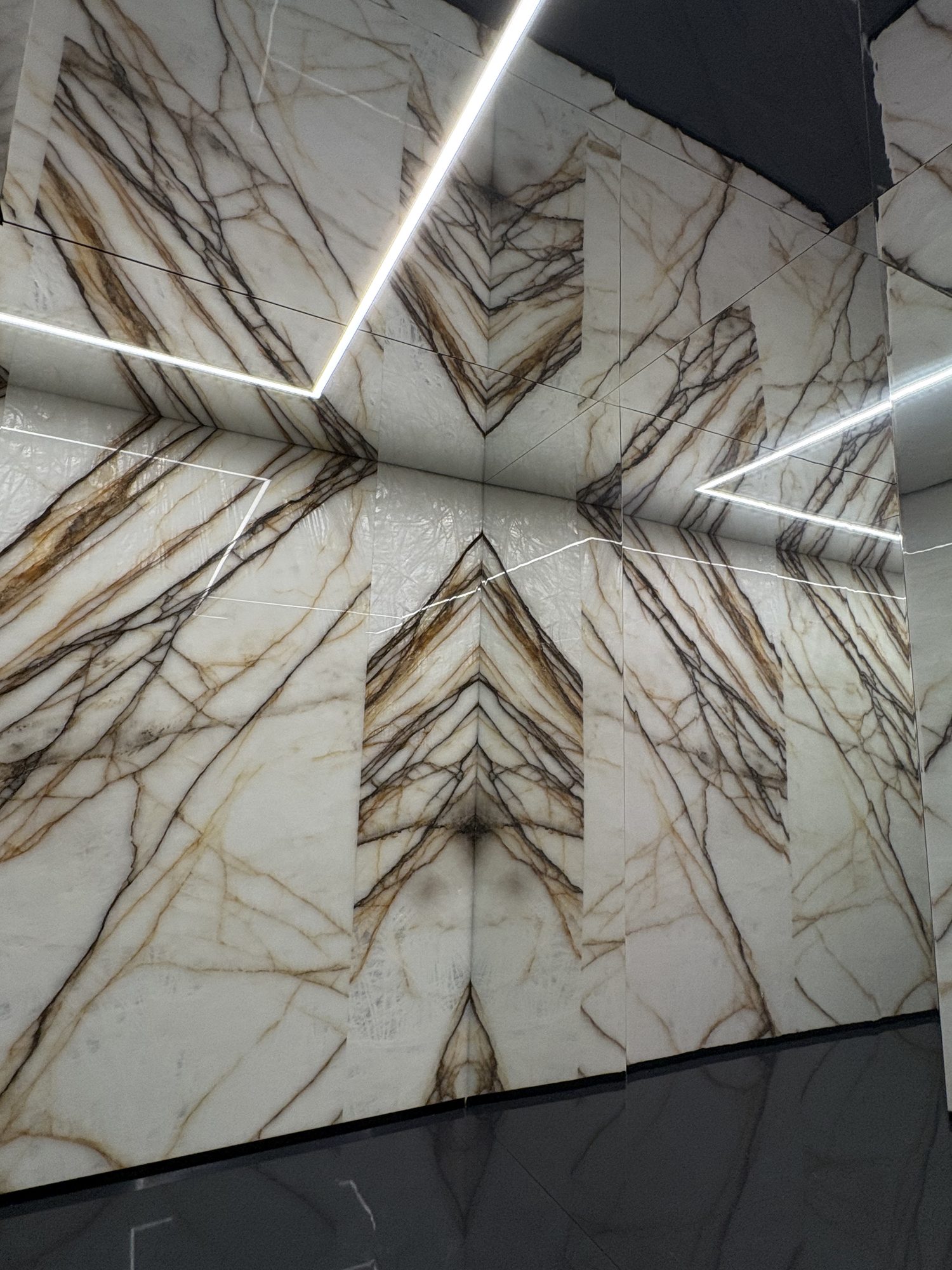 Mirrored ceiling reflecting bookmatched stone panels at the Antolini installation, Marmomac 2026
