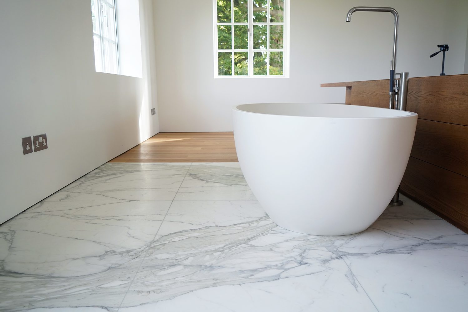 A freestanding bath on a Calacatta Oro marble floor, Oxford - Roma Marble