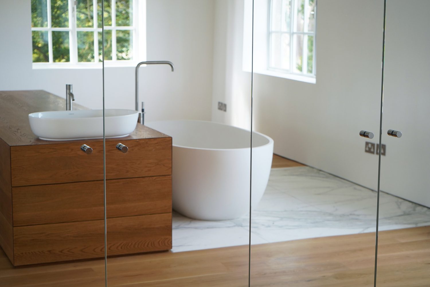 A Calacatta Oro bathroom with a timber vanity and freestanding bath, Oxford - Roma Marble