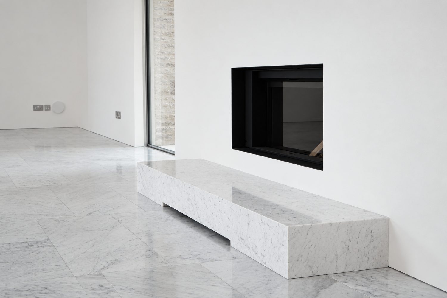 A solid Carrara marble bench beneath an inset fire, Oxford - Roma Marble