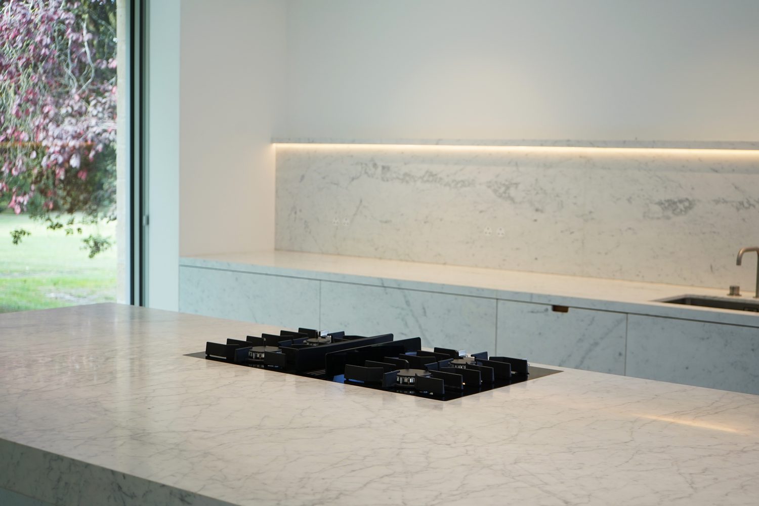 A hob set flush into a Carrara marble worktop, Oxford - Roma Marble
