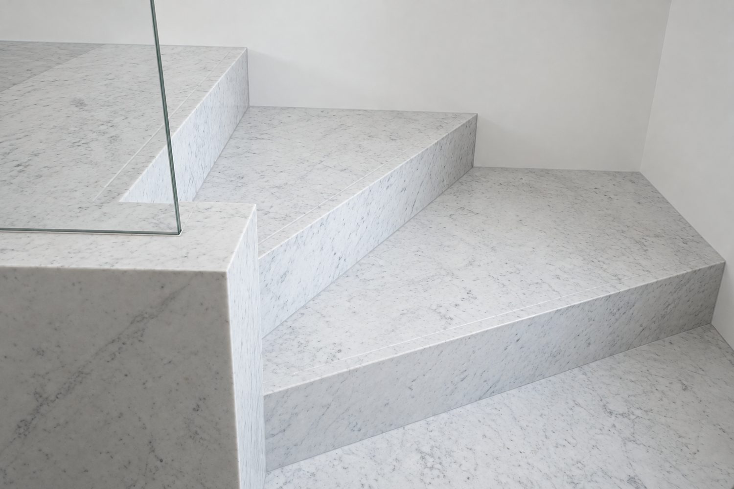 Detail of Carrara marble stair treads against a glass balustrade, Oxford - Roma Marble